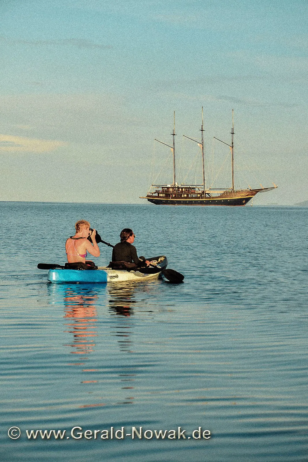 Two people floating on inflatable rings in deep blue water.