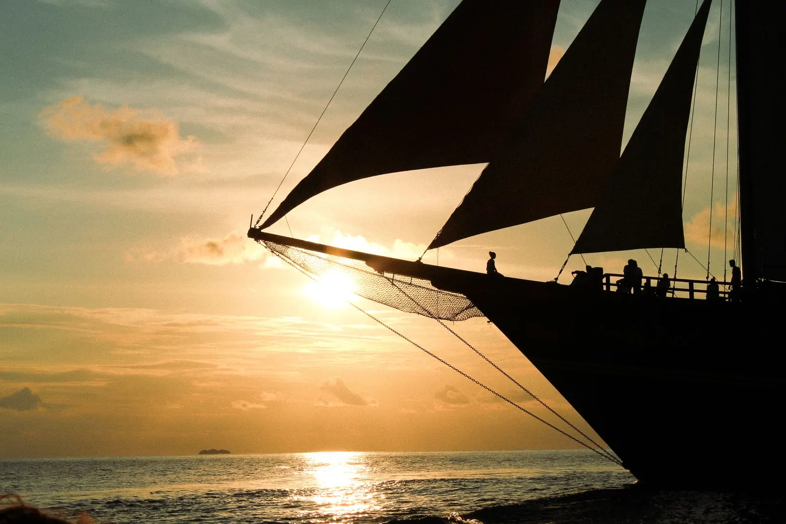 Waow 2's bow at sunset, sails silhouetted.