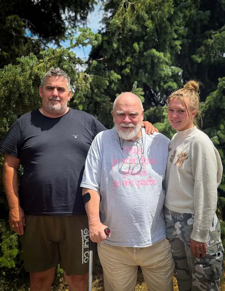 Michel standing outdoors between a man and a young woman