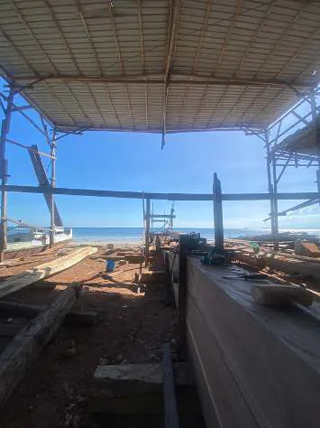 Keel timber laid out under the open shipyard shelter by the sea