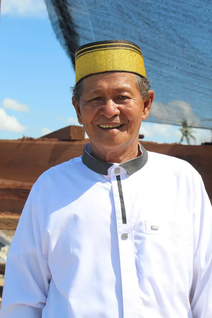 Portrait of Master Haji Wahab in a white shirt and gold cap