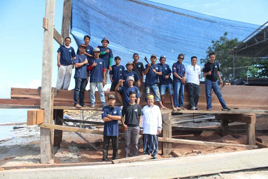 Haji Wahab and his team of shipbuilders posing on the keel timbers