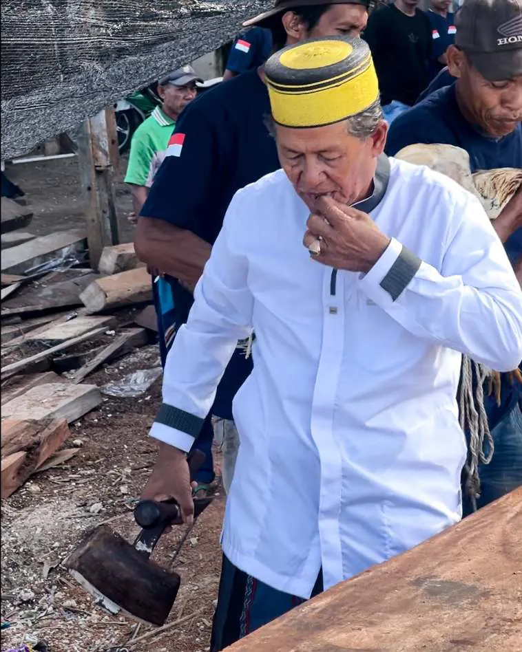 Pak Haji Wahab tasting a piece of wood, an adze in his other hand