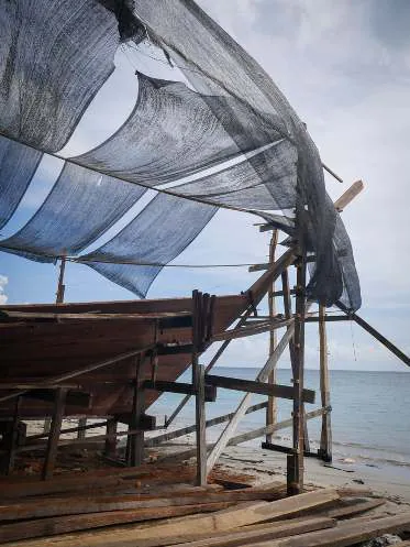 The bow rising on its scaffolding, with the sea behind