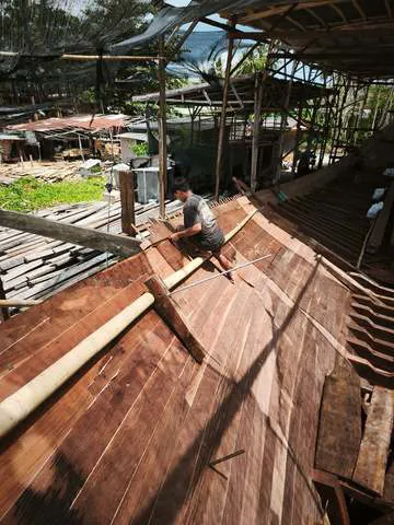 A worker fitting planks along the side of the hull