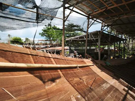 The planked side of the hull with the shipyard sheds behind