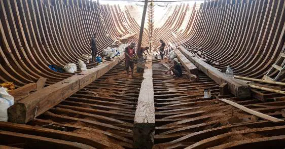 Shipwrights at work inside the ribbed hull