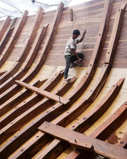 A shipwright climbing the ribs of the hull