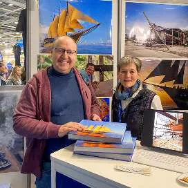 A visitor holding the book La Légende du WAOW at the booth
