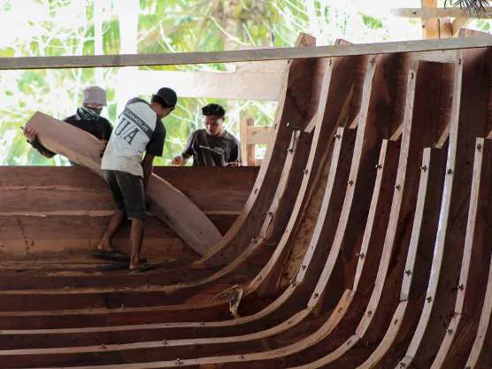 Shipbuilders carrying a rib piece inside the hull