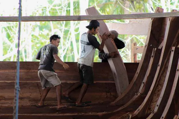 Two shipbuilders lifting a rib into place