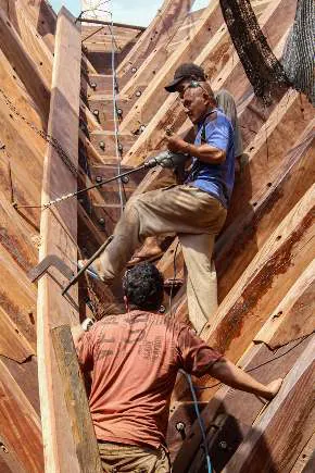 Two shipbuilders climbing inside the narrow bow section