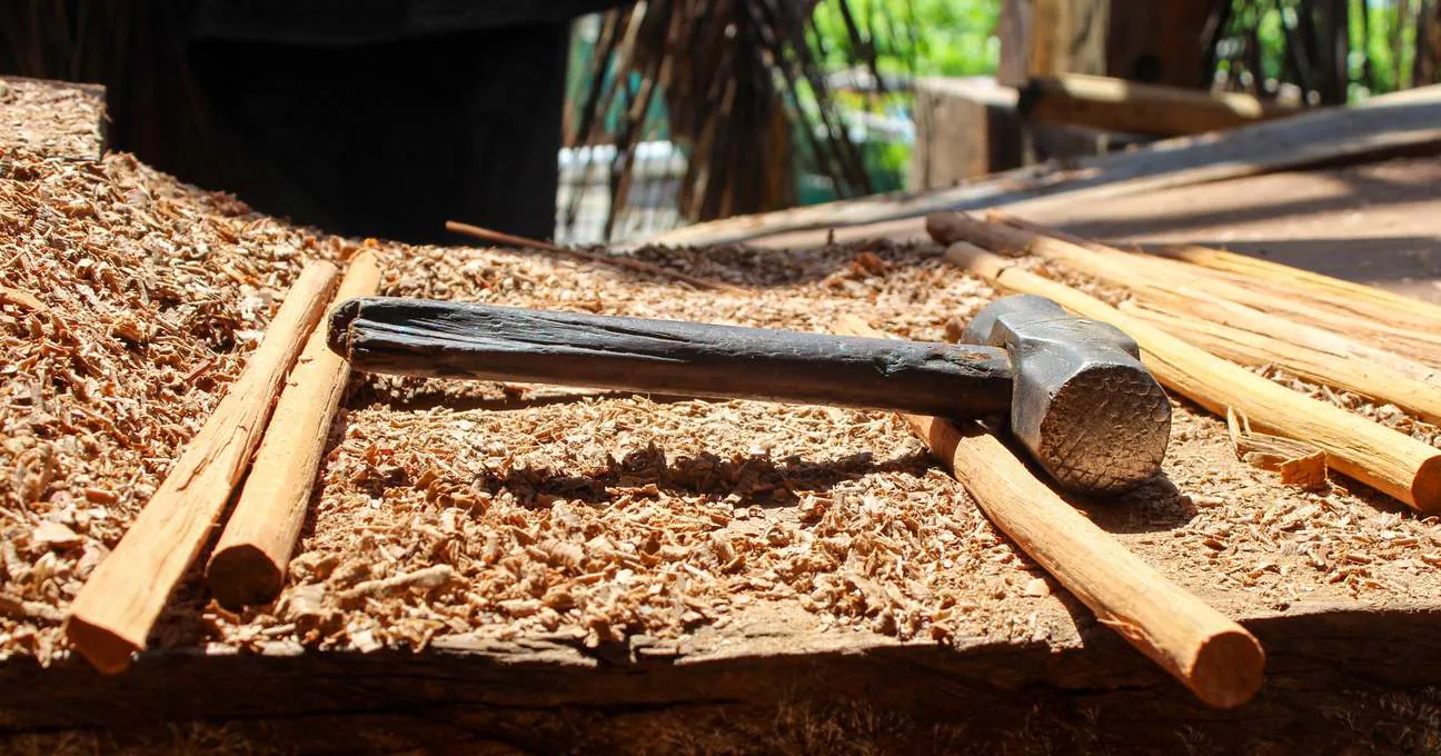 A wooden mallet and an iron hammer on wood shavings