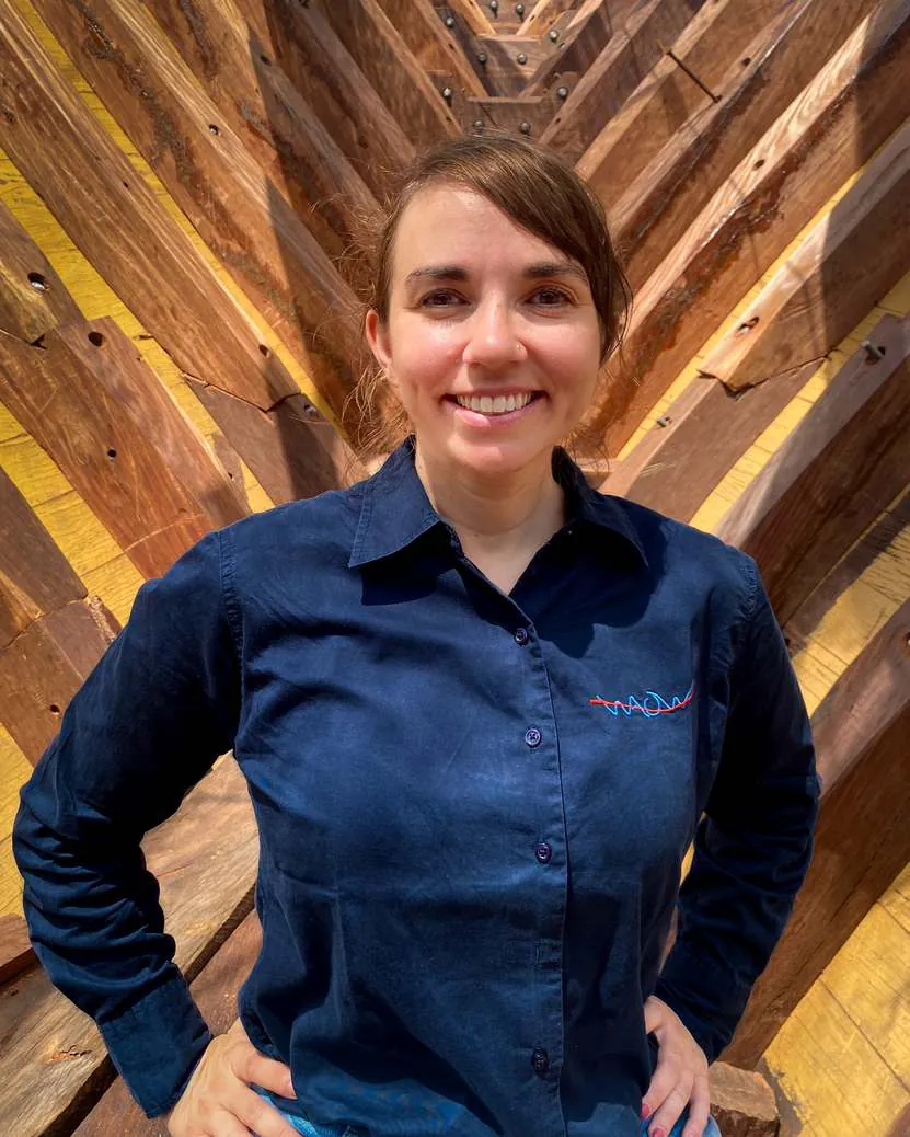 Portrait of Lorine Grandjean in a navy WAOW shirt in front of wooden planking