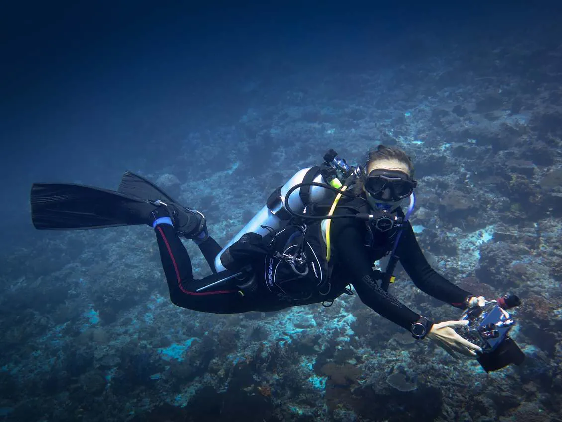 Lorine diving over a reef with an underwater camera