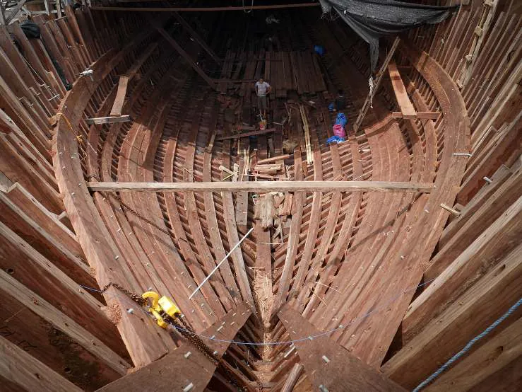 Looking down into the hull toward the bow, workers on the planking