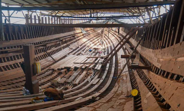 Inside the hull of WAOW 2 under the shipyard roof, with ribs and planking