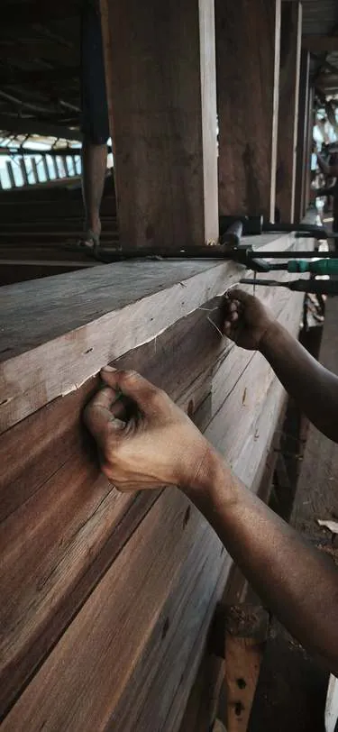 Close-up of a hand working fibre into a seam of the hull