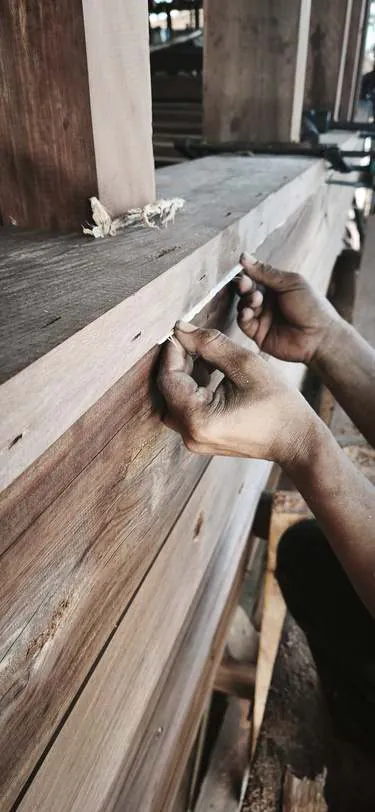 Hands pressing caulking fibre into a plank seam