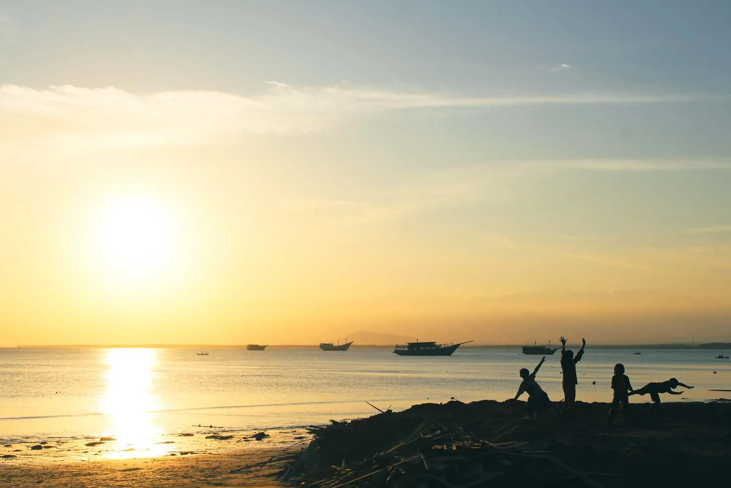 Sunset over the sea at Bira, with children's silhouettes playing on the shore