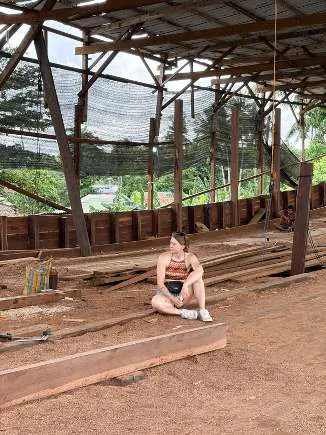 Camille sitting on a timber on the shipyard floor