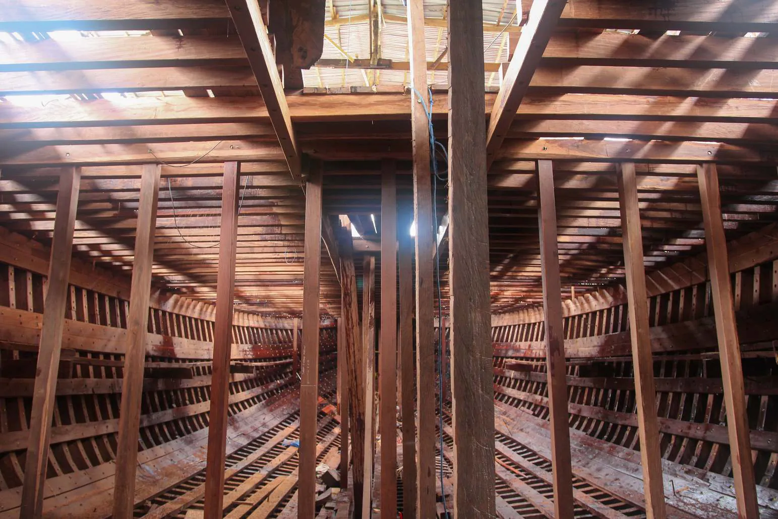 Interior of the hull with vertical supports and light falling through the deck