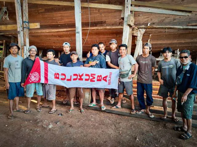 Part of the shipyard team holding a red and white Bulukumba banner inside the shipyard on Indonesian Independence Day