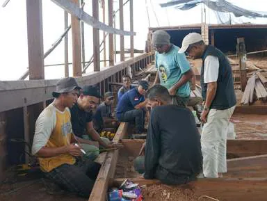 Shipbuilders and team members discussing plans sitting on the deck