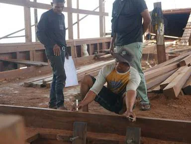 Craftsmen measuring and marking timber on the deck