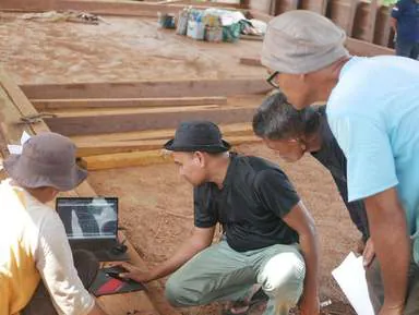 Team members gathered around a laptop on the deck to review plans