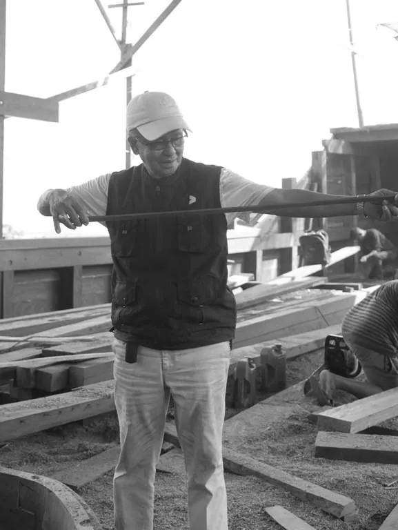 Black-and-white photo of a man holding out a tape measure on deck