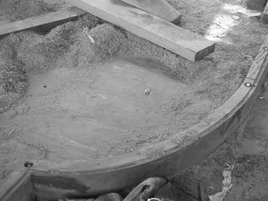 Black-and-white close-up of a curved wooden section filled with sawdust