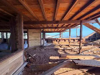 An open area of the main deck under the wooden ceiling, with timber on the floor