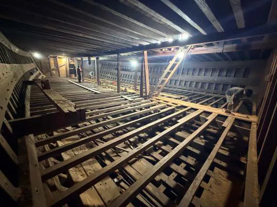 The lower deck lit by work lamps, showing the new floor beams dividing it into two levels