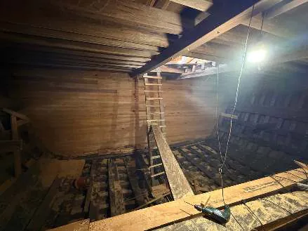 A ladder leading down into the lowest level of the hull, lit by a work lamp